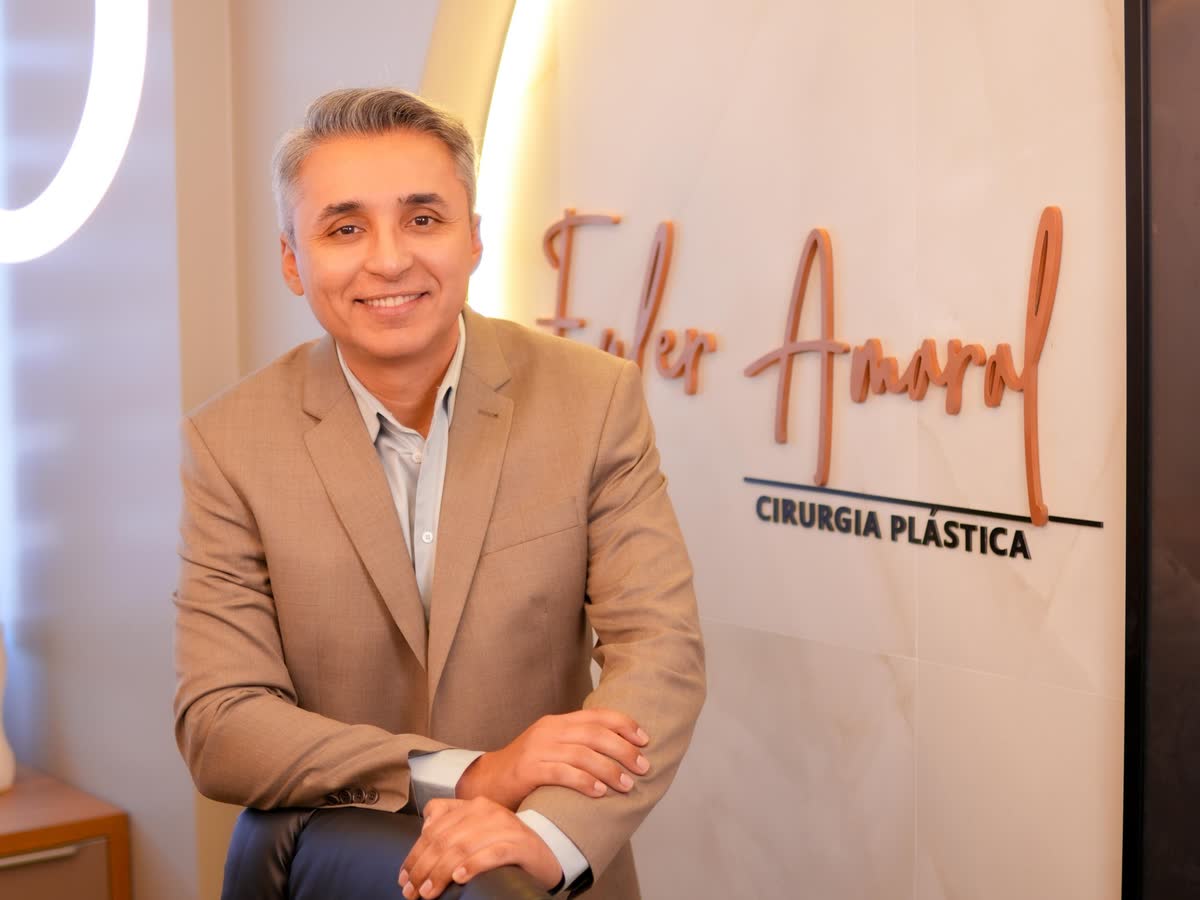 Dr. Euler Amaral de blazer bege ao lado do letreiro Euler Amaral Cirurgia Plástica, no consultório em Santarém